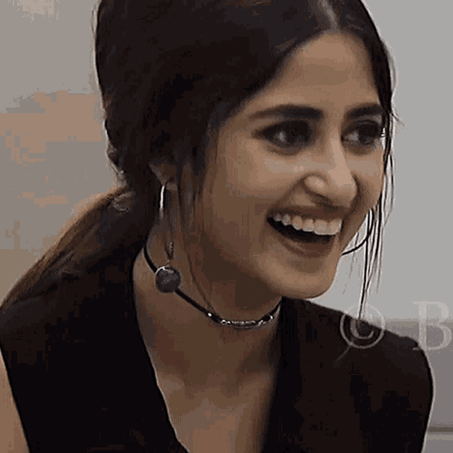 a woman wearing a choker and hoop earrings smiles