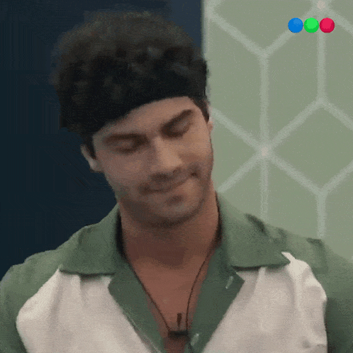 a man wearing a headband and a green and white shirt is smiling