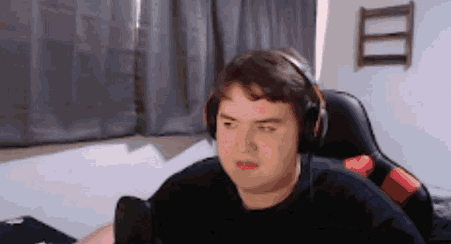a man wearing headphones is sitting in a chair in front of a microphone .