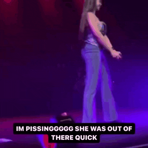 a woman is standing on a stage in front of a purple light and a microphone .