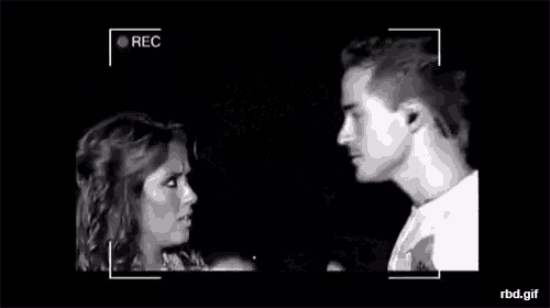 a man and a woman are kissing in front of a camera .