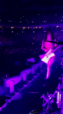 a woman in a red dress is dancing in front of a crowd at a concert