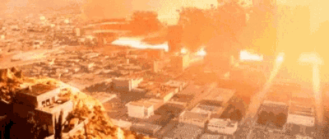 an aerial view of a city with a large explosion in the background