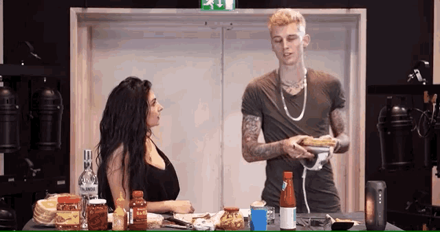 a man and a woman are sitting at a table with a bottle of vodka in the background