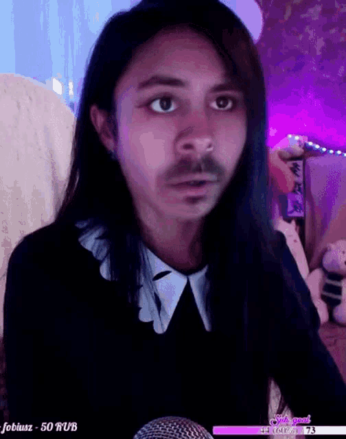 a man with long hair and a mustache is sitting in front of a microphone ..