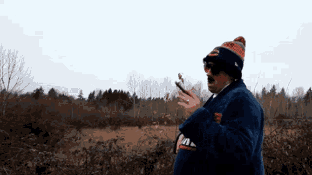 a man wearing a bears hat and sunglasses is standing in a field