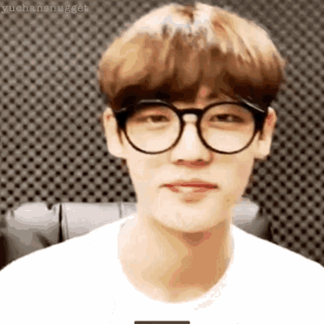 a close up of a young man wearing glasses and a white shirt .