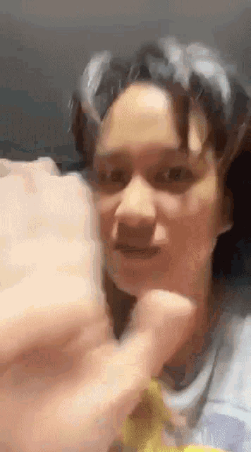 a close up of a person 's face with a hand reaching out towards it .