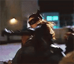 a woman in a batman costume is sitting on a man 's shoulders