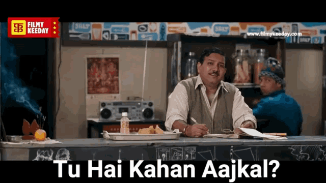 a man sitting at a counter with the words tu hai kahan aajkal written on the bottom