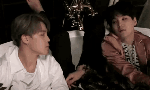 a couple of men are sitting next to each other on a bed .