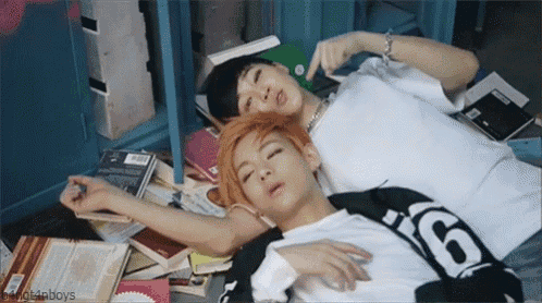 two young men are laying on the floor with their eyes closed and one has the number 6 on his shirt .