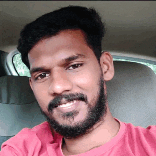 a man with a beard wearing a red shirt is smiling