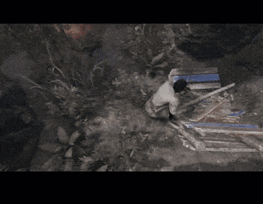a man in a white shirt is kneeling down in a dark forest