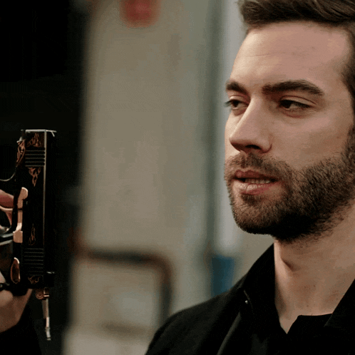 a man with a beard is holding a gun with the letter a on it