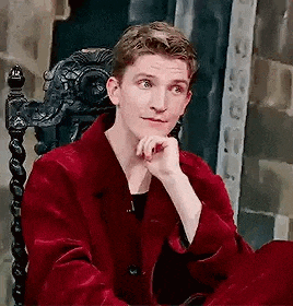 a young man in a red coat is sitting in a chair .