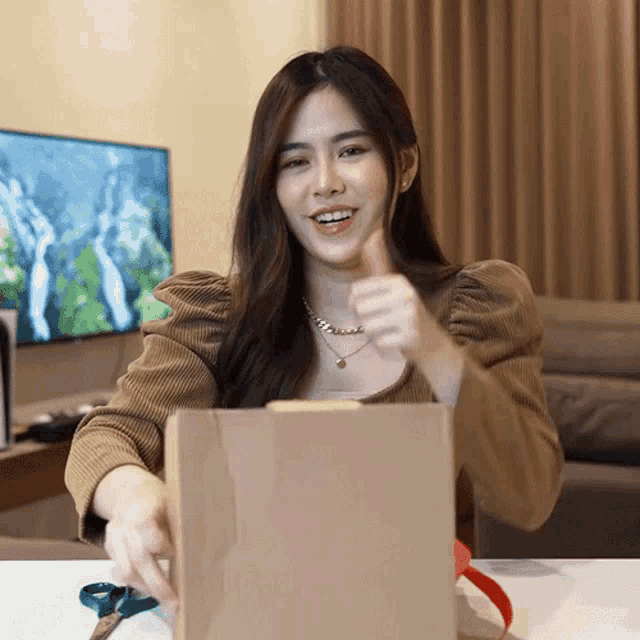 a woman giving a thumbs up while holding a brown bag