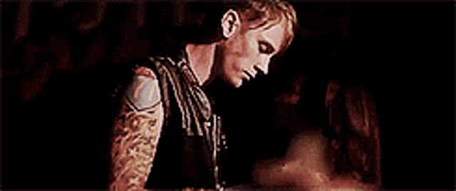 a man with a tattoo on his arm is sitting next to a woman .