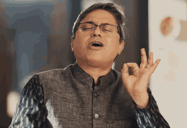 a man wearing glasses is making an ok sign with his hand