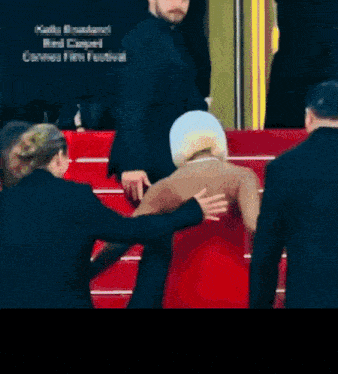 a woman in a red dress is being helped up a set of red stairs