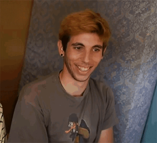 a young man wearing a t-shirt with a picture of a skateboarder on it smiles