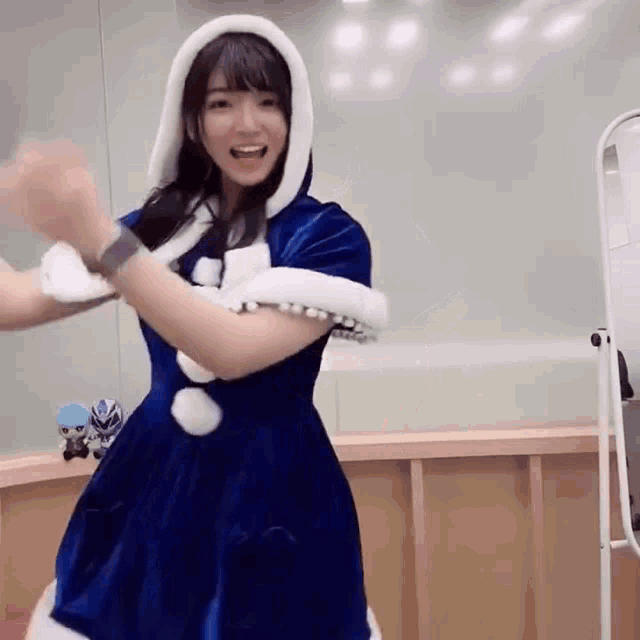 a woman in a blue dress and white hood is dancing .