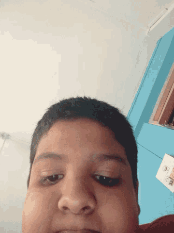 a close up of a child 's face with a blue wall behind him