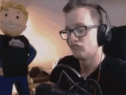 a man wearing headphones and glasses is sitting in front of a microphone and making a funny face .