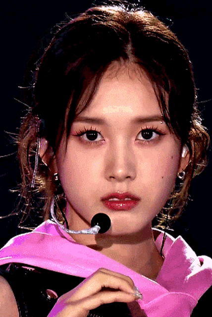 a close up of a woman 's face with a pink ribbon around her neck
