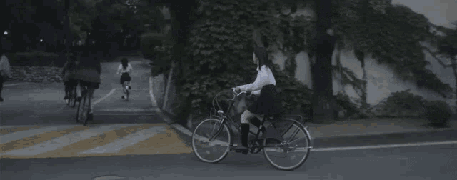 a girl in a school uniform is riding a bike