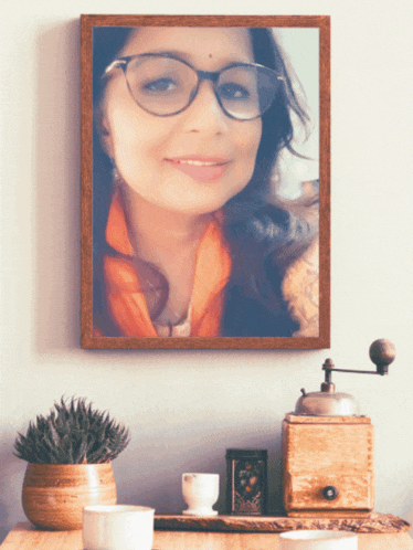 a framed picture of a woman wearing glasses is hanging on a wall