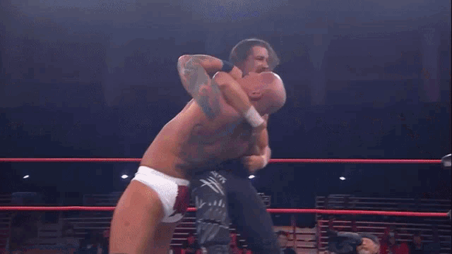 two wrestlers are wrestling in a ring with a referee watching