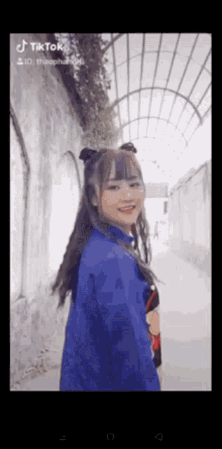 a girl in a blue shirt is standing in a hallway .