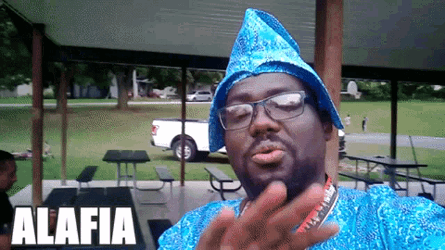 a man wearing glasses and a blue hat is standing under a canopy with the word alafia on the bottom