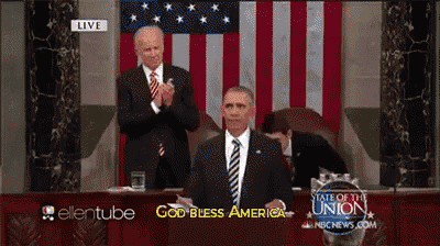 a man in a suit and tie is giving a speech in front of an american flag and says god bless america