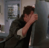 a man is standing in front of a refrigerator covering his face with his hands