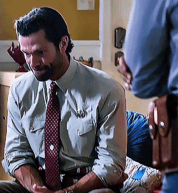 a man in a shirt and tie with a badge on his chest