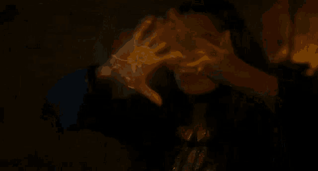 a woman is holding her hands up in the air while a glowing hand is projected on her face .