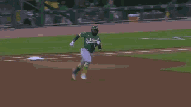a baseball player is running towards the base while another player watches on .