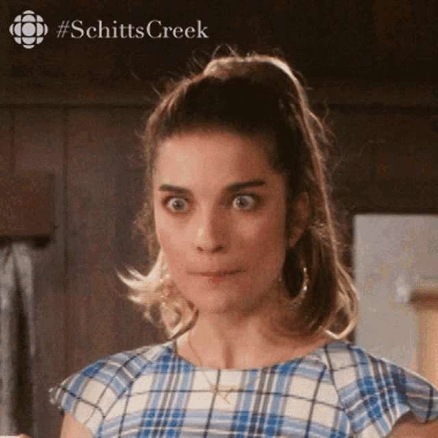 a close up of a woman 's face with a #schittscreek logo in the background