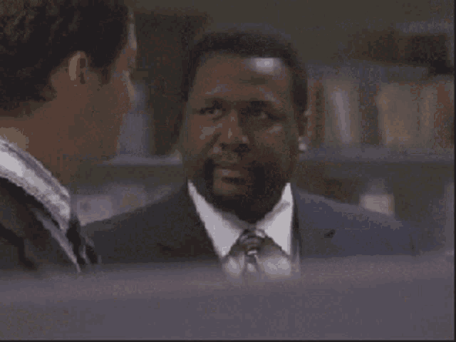 a man in a suit and tie talks to another man