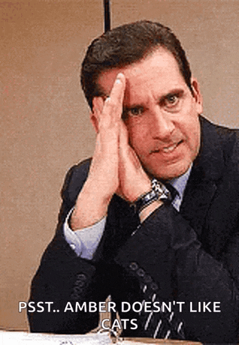 a man in a suit and tie is sitting at a desk with his hands on his forehead .