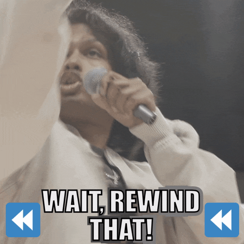 a man singing into a microphone with the words wait rewind that behind him