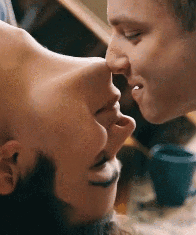 a man and a woman are kissing each other on the nose in a close up .