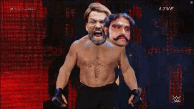 a shirtless wrestler is standing next to a man with a mustache in front of a live screen