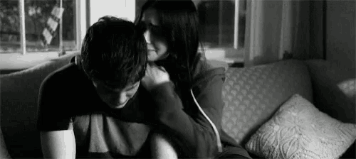 a man and a woman are hugging each other on a couch in a black and white photo .