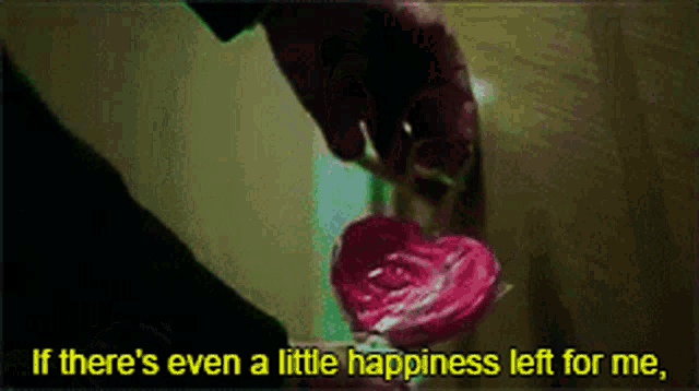a person is holding a pink heart shaped lollipop with the words " if there 's even a little happiness left for me "