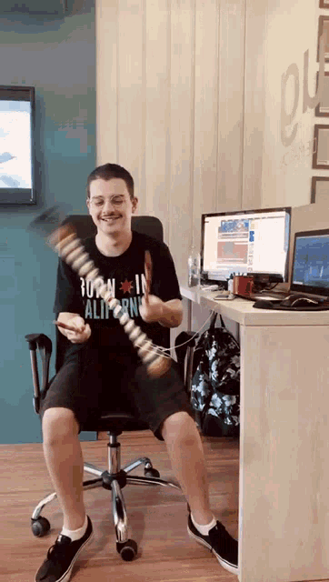 a man wearing a shirt that says turn in california sits in an office chair