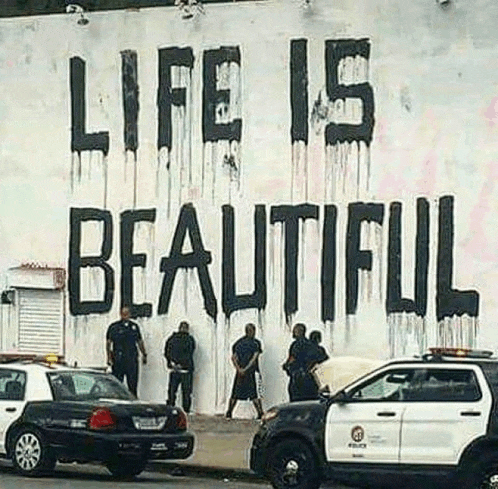 police officers are standing in front of a wall that says life is beautiful