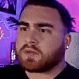 a man with a beard is making a funny face in front of a computer monitor .